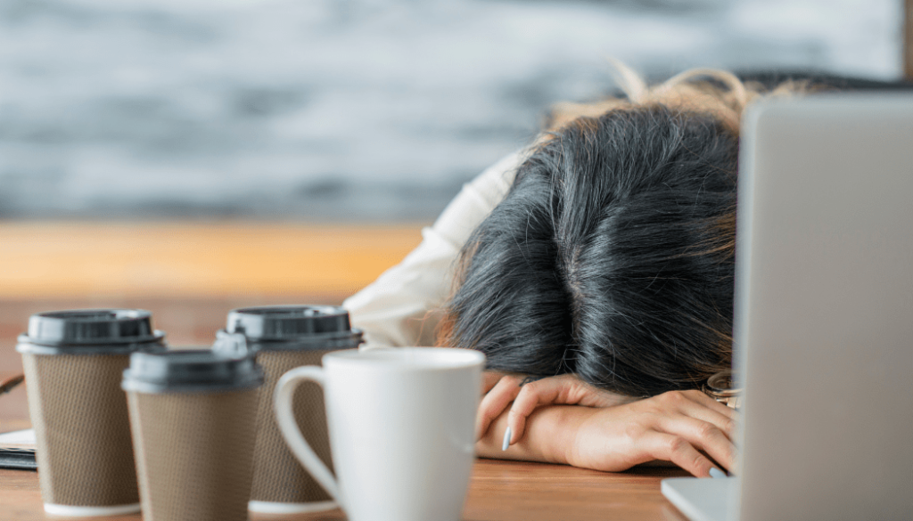 femme dort sur son ordinateur entourée de tasses de café